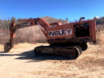 Orange and Black Tractor Next to Piles of Rocks